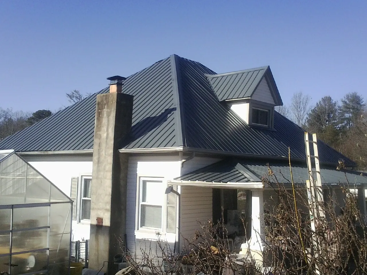 Dark blue standing seam metal roof on a white farmhouse with dormer — Slate & Tile Roof Repair by Roofing Brothers in Harrington