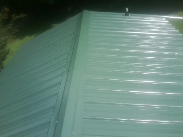 New green metal panels meeting at the ridge of a roof — Flat Roof Repair work by our crew in Harrington