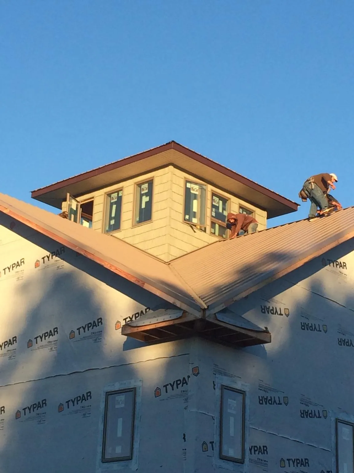 Roofers working around a rooftop cupola on a new metal roof at sunset — Roof Waterproofing in Harrington by Roofing Brothers